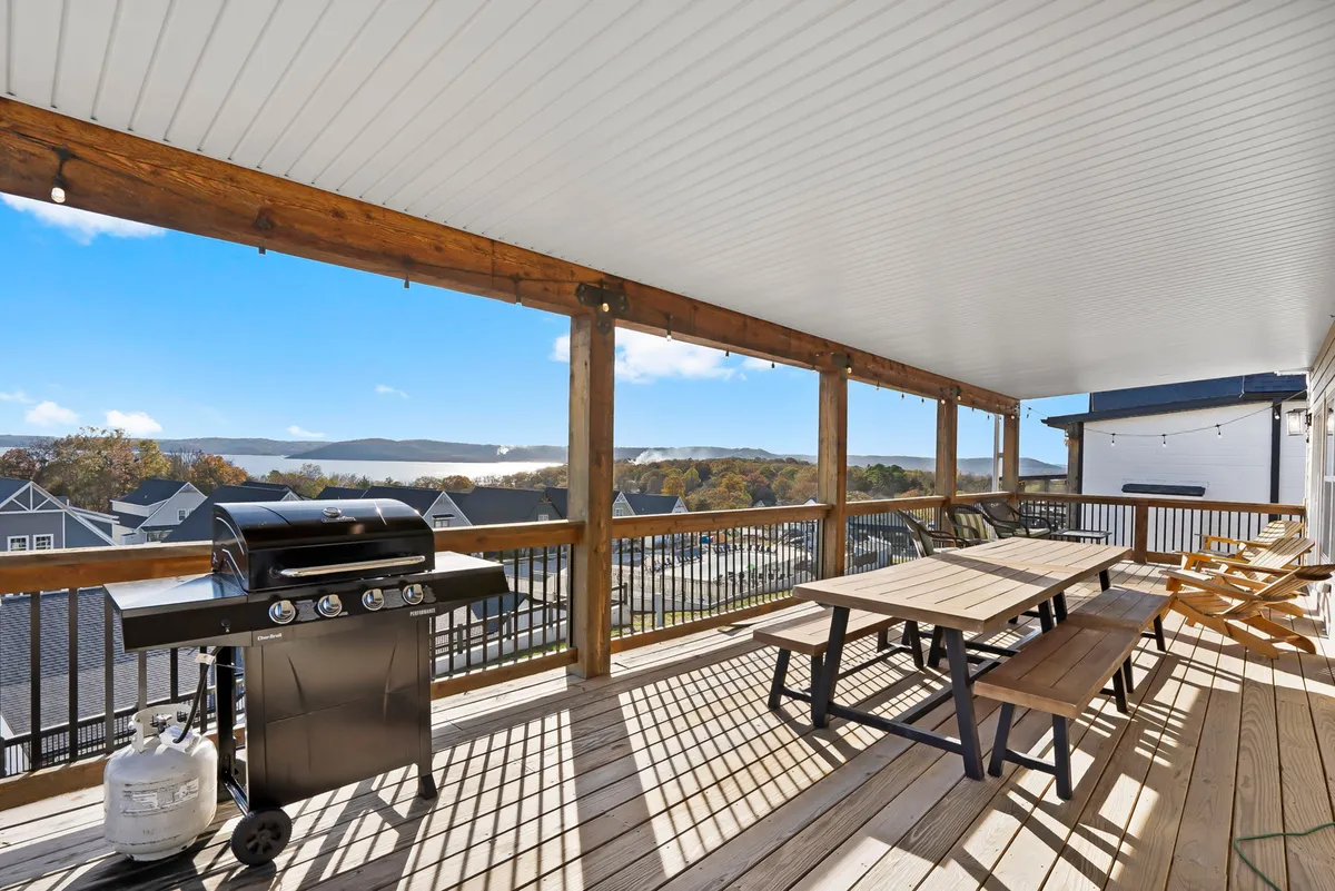 An inviting outdoor dining area with a grill and dining table set against a backdrop of rolling mountains. The scene suggests a laid-back meal, with space for friends and family to gather and enjoy the view.