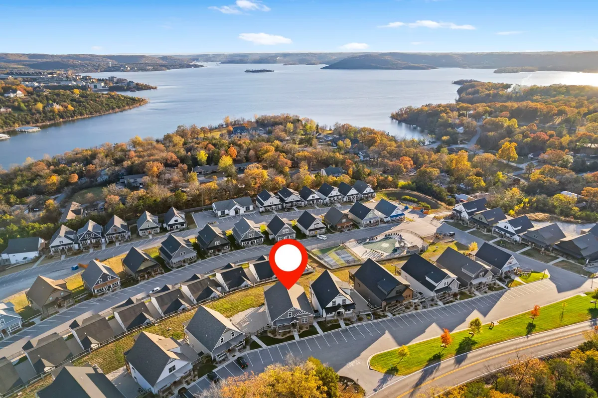 This exterior image features a broad lake view framed by autumn foliage, with a well-laid-out neighborhood visible along the shoreline. The tranquil water and surrounding landscape evoke a sense of both relaxation and natural beauty, which is ideal for guests seeking a retreat close to outdoor activities like golf.