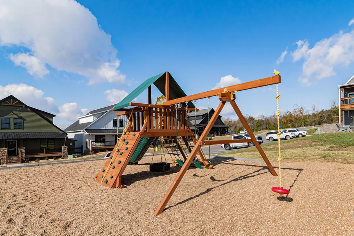 A cheerful exterior shot of a playground structure with a swing and slide, set in an open green area. Children are shown playing, while families gather nearby, creating a lively and joyful atmosphere. The image captures the fun, inclusive spirit of group and family activities available on-site.